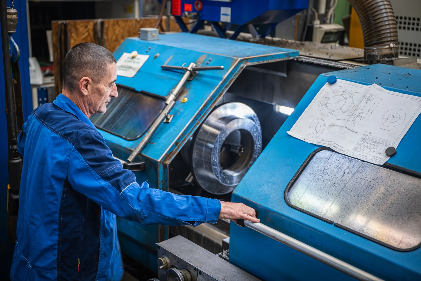 Dreher im blauen Arbeitsanzug an der Drehmaschine bei BC-TestTec